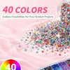 A pile of 40 colors of 3mm flatback resin jelly rhinestones with adhesive craft gems scattered on a pink surface.