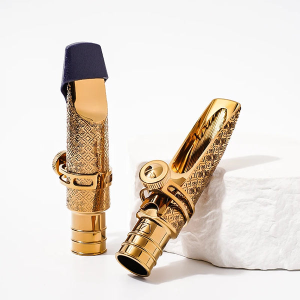 A gold-plated tenor saxophone mouthpiece with a black cap resting on a white surface.