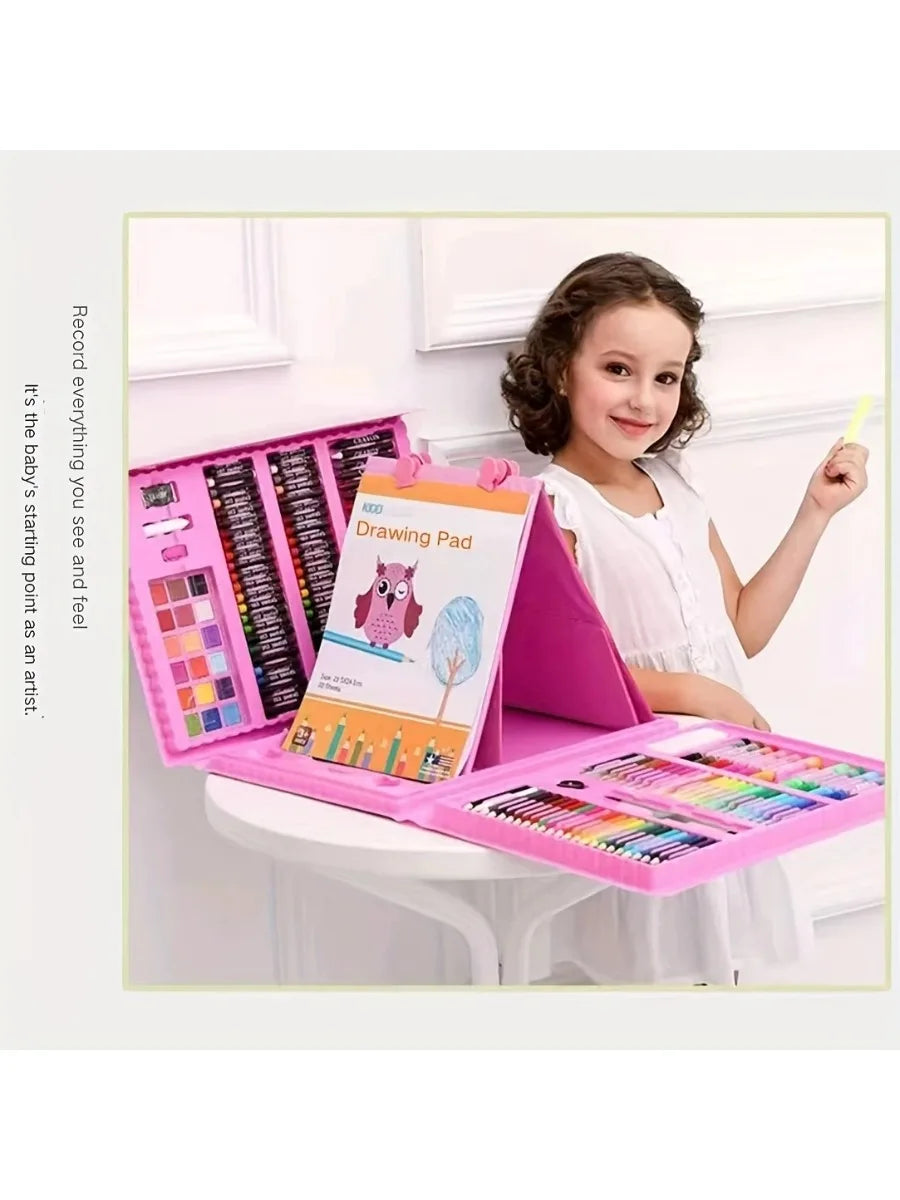 A young girl is using a pink drawing pad and an art set with various colored pencils and crayons on a white table.
