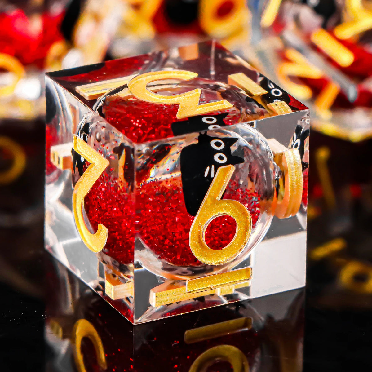 A clear resin die with a red glitter core and gold lettering, reflecting on a dark surface.