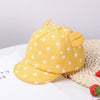 A yellow baby cotton baseball cap with cute rabbit ears resting on a white surface.