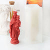 A reddish-pink silicone figure mold depicting a woman and child, next to a white pillar candle.