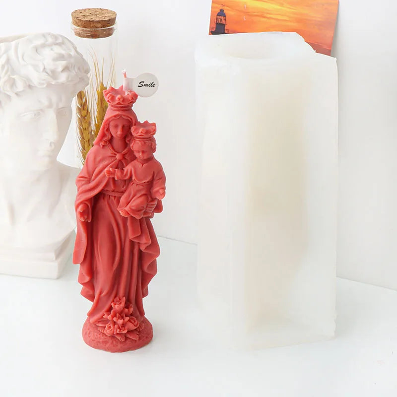 A reddish-pink silicone figure mold depicting a woman and child, next to a white pillar candle.