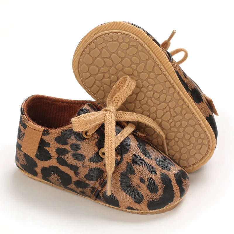 A pair of leopard print soft sole baby sneakers shown from the side.