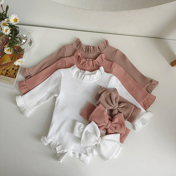 A set of three knitted tops in white, pink, and beige with ruffled sleeves and a bow detail.