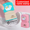 A hand holds a customized name stamp featuring a yellow elephant and a lion in a bathtub design on a white background.