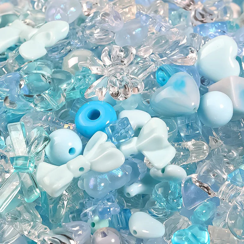 A close-up of mixed clear and light blue acrylic loose beads for jewelry making.