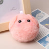 A pink squeaky plush pig keychain with black eyes resting on a wooden frame.