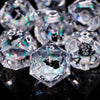 A close-up of a set of clear polyhedral dice, including a d10 and d8, reflecting light on a dark surface.