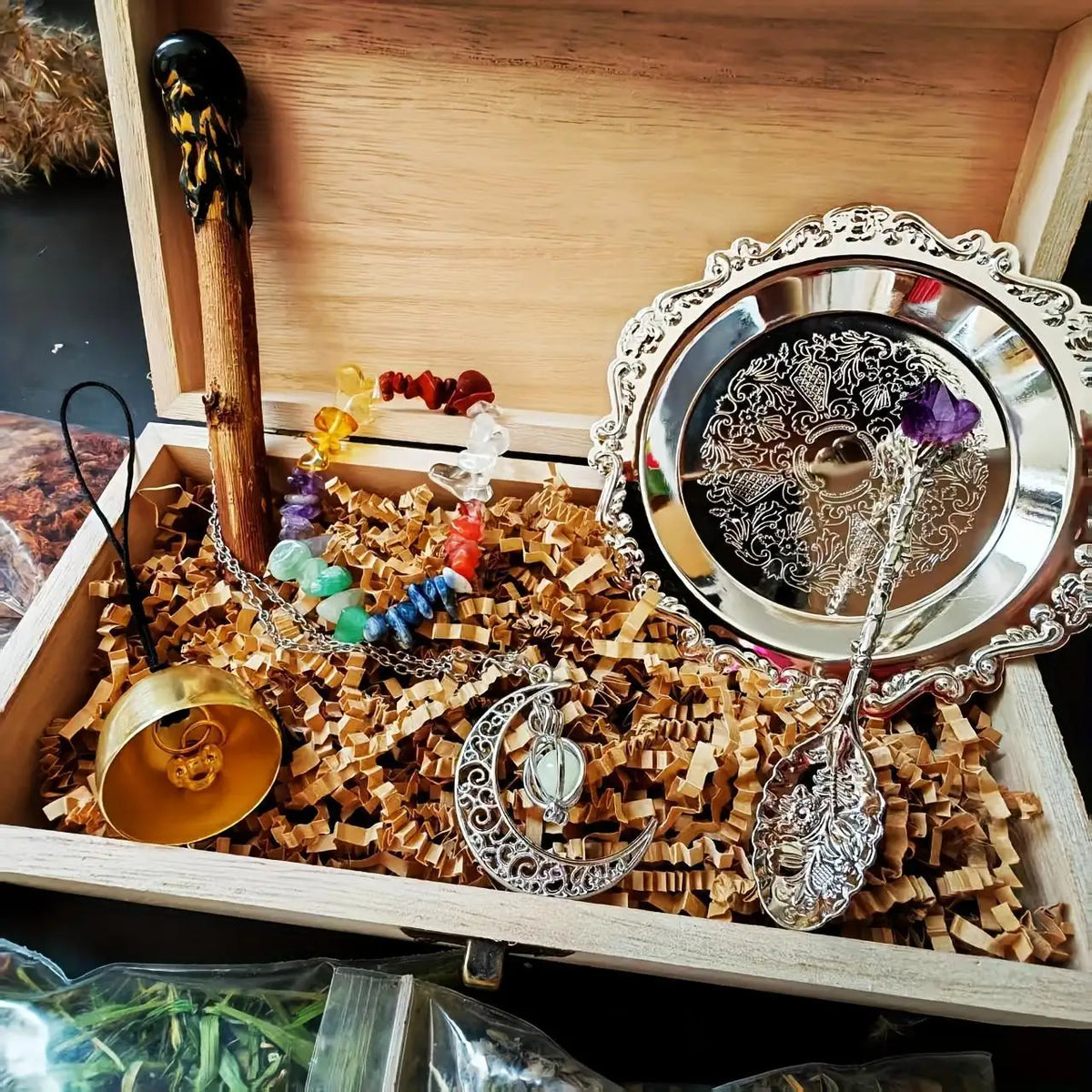 A wooden box contains a witchcraft starter kit with crystals, herbs, and a silver bowl.