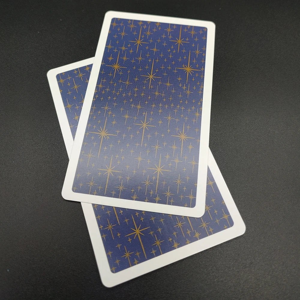 A vertical tarot card featuring a blue background with gold star patterns, lying next to another card.