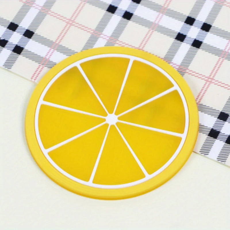 A yellow citrus fruit coaster with a cross-section pattern rests on a white and black plaid cloth.