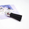 A close-up of black velvet tassels with silver metal findings resting on a white background.
