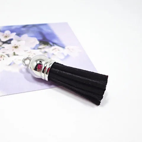 A close-up of black velvet tassels with silver metal findings resting on a white background.