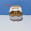 A white plush cat doll shaped like a milk carton with gold lettering, shown against a blue background.