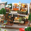 A detailed wooden miniature dollhouse assembly kit featuring a storefront and interior with furniture.