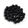 A pile of small, round, black imitation pearl beads for jewelry making.