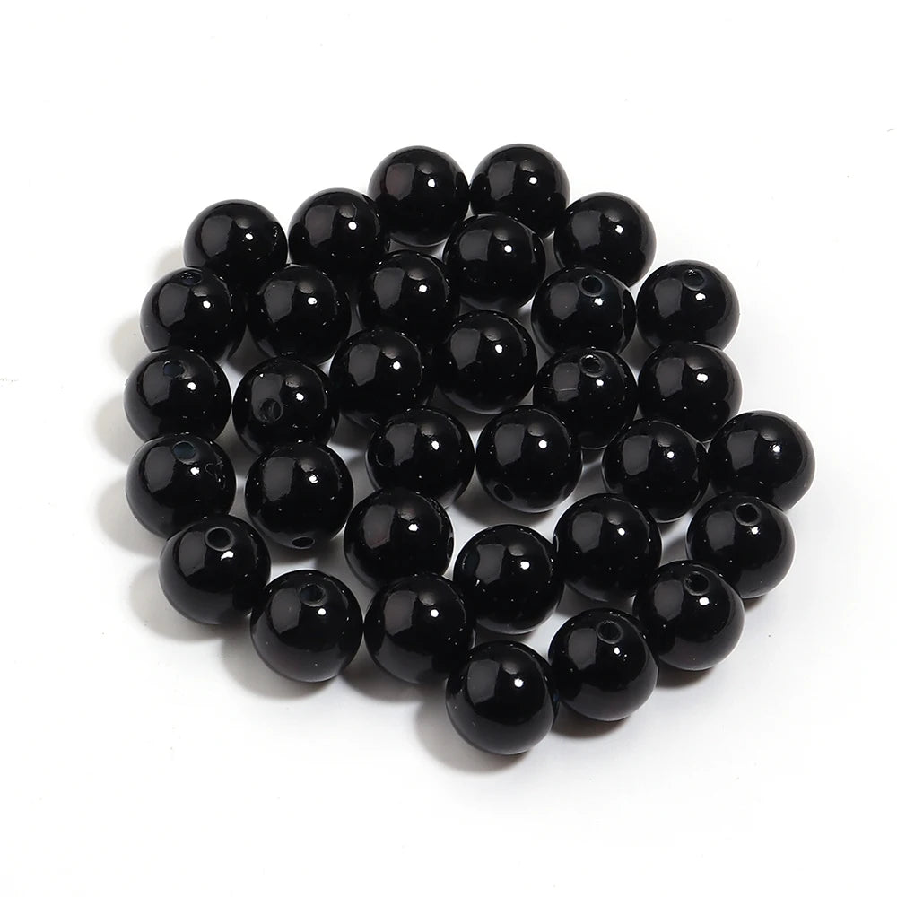 A pile of small, round, black imitation pearl beads for jewelry making.