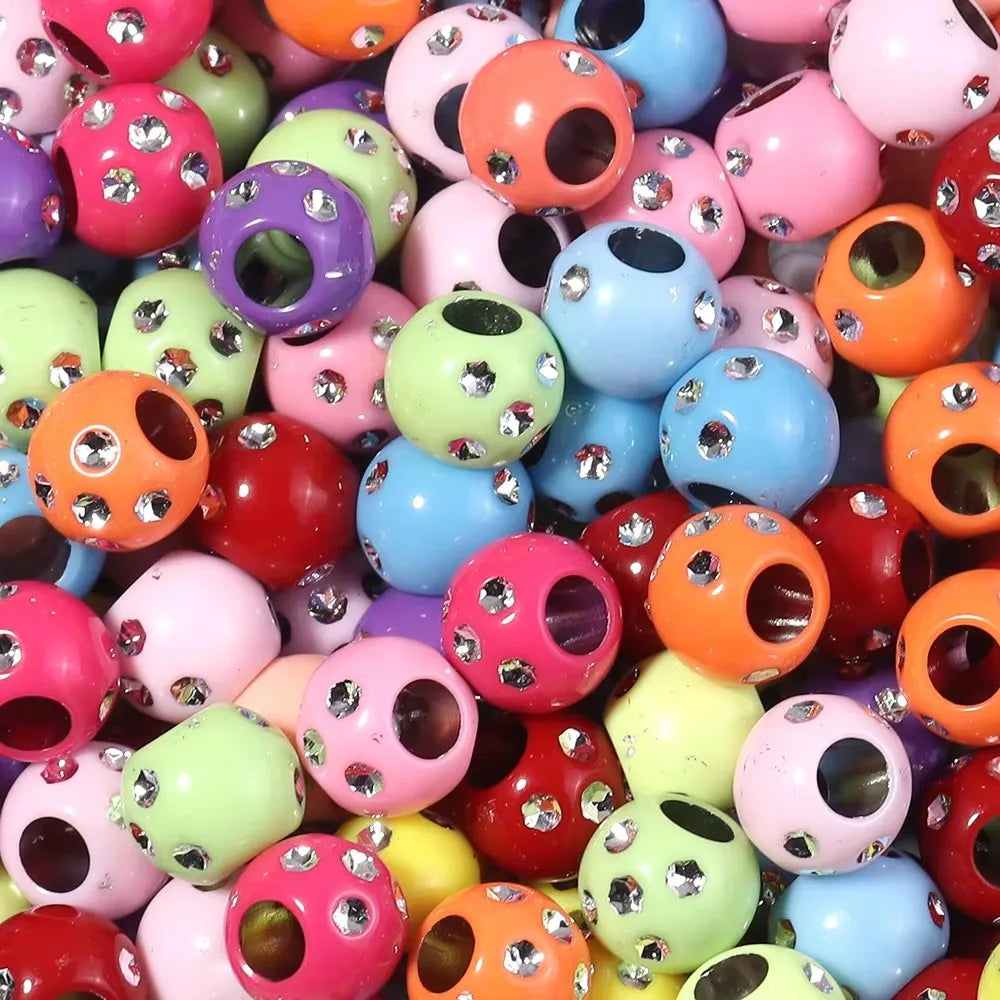 A close-up view of various colorful rhinestone acrylic spacer beads in various shapes and sizes.