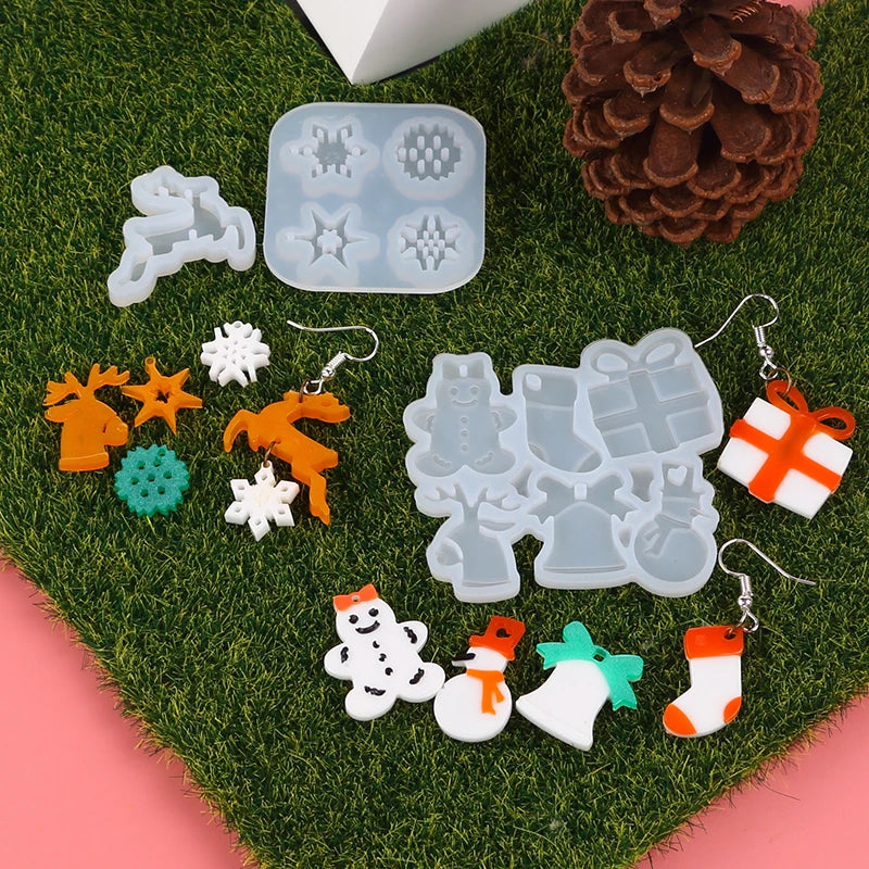 Silicone molds shaped like reindeer, snowflakes, and gifts for jewelry and craft projects on green moss.