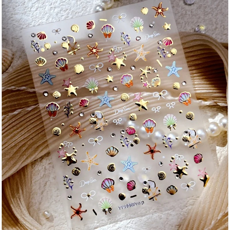 Clear sticker sheet featuring gold and iridescent 3D ocean-themed nail art stickers like starfish and shells