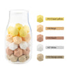 A clear glass bottle filled with 15 hexagonal silicone beads in various shades of yellow, beige, peach, and white.