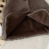 A close-up of a dark brown plush fleece vest with a contrasting tan panel, showing the texture and layered design.