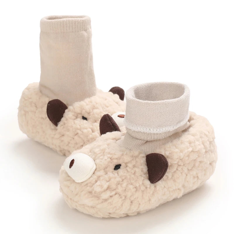 A pair of adorable cartoon baby booties shaped like a white polar bear, featuring soft, fuzzy material and light beige fabric
