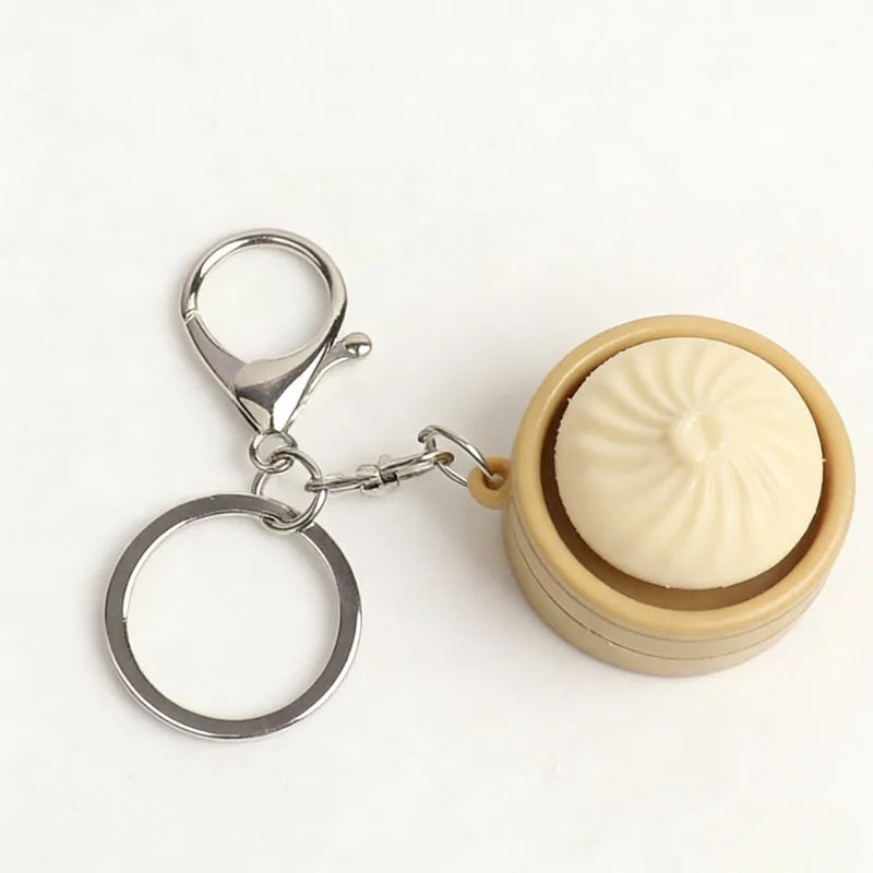 A small, light beige steamed bun fidget toy attached to a silver keychain ring.
