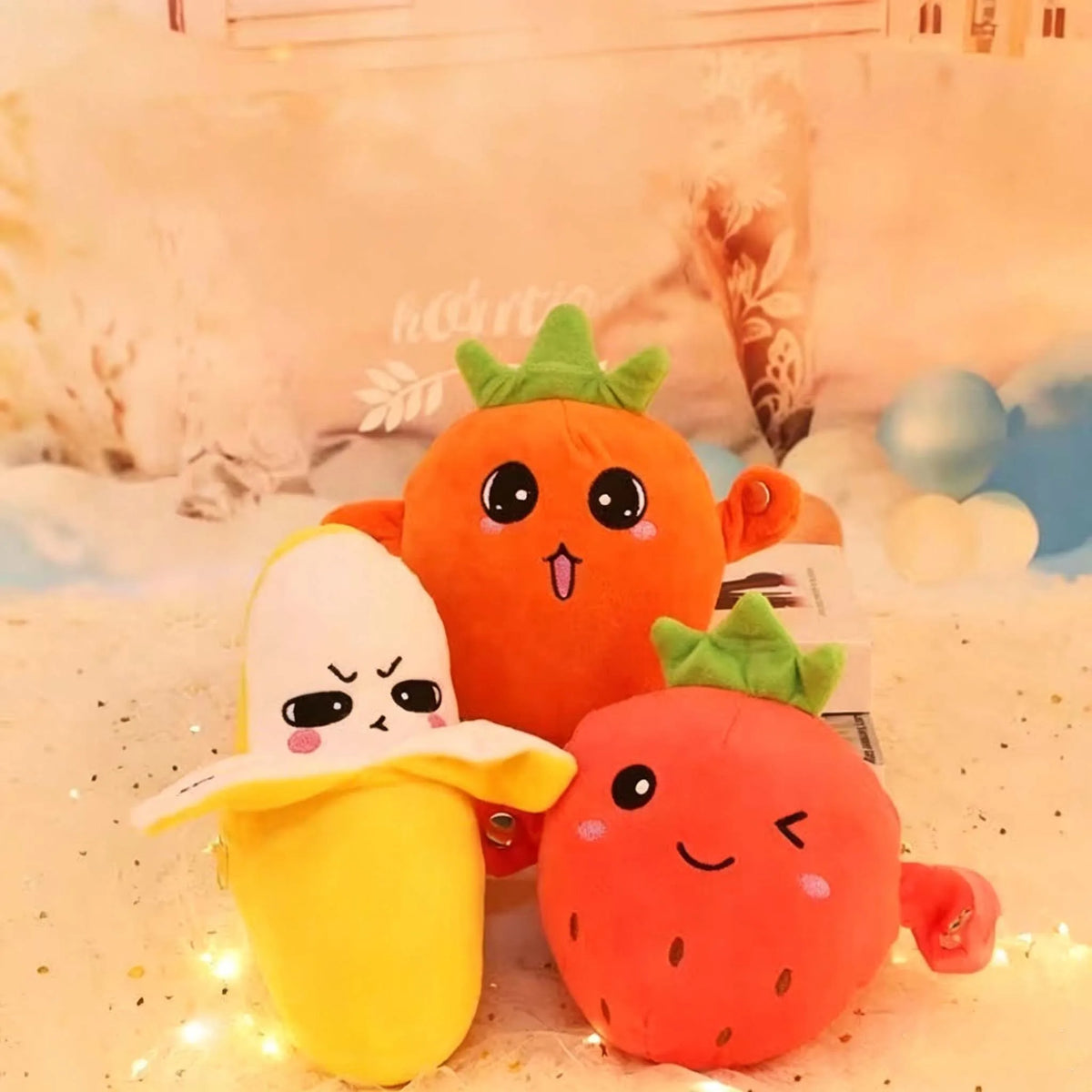 An orange carrot and a red strawberry plush toy sitting on a white surface.