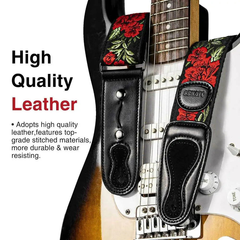 A black leather guitar strap featuring a floral pattern, complete with picks and locking mechanisms.