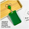 A green retractable ID badge holder with a clip is placed on a wooden tray next to a keychain.