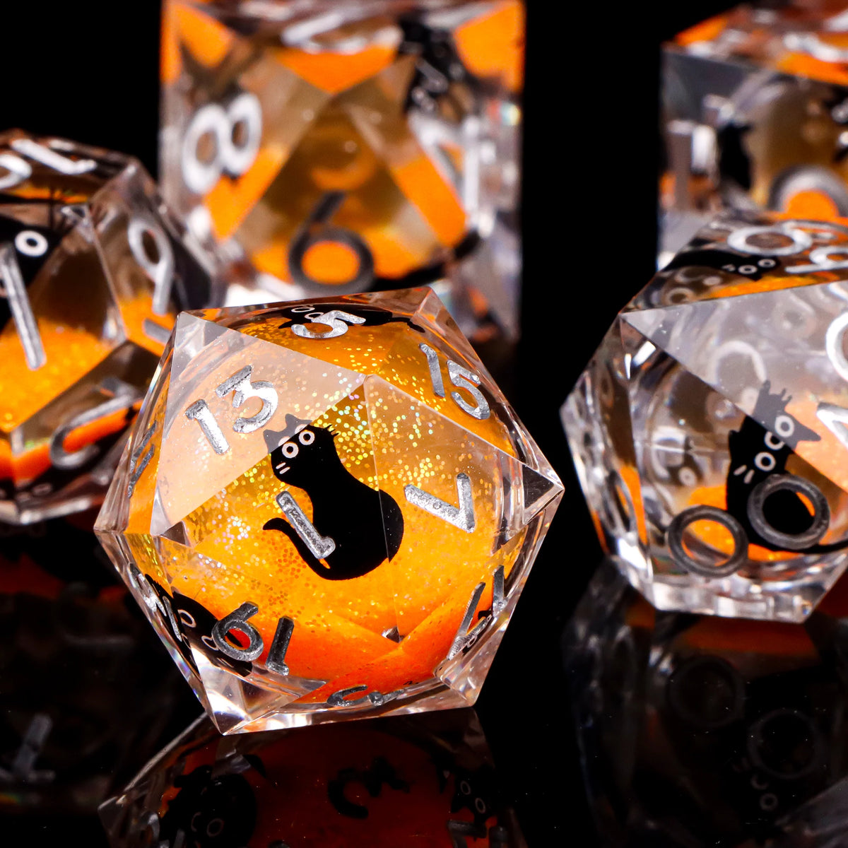 A close-up of a set of liquid core dice featuring black cats and orange glitter inside clear glass cubes.