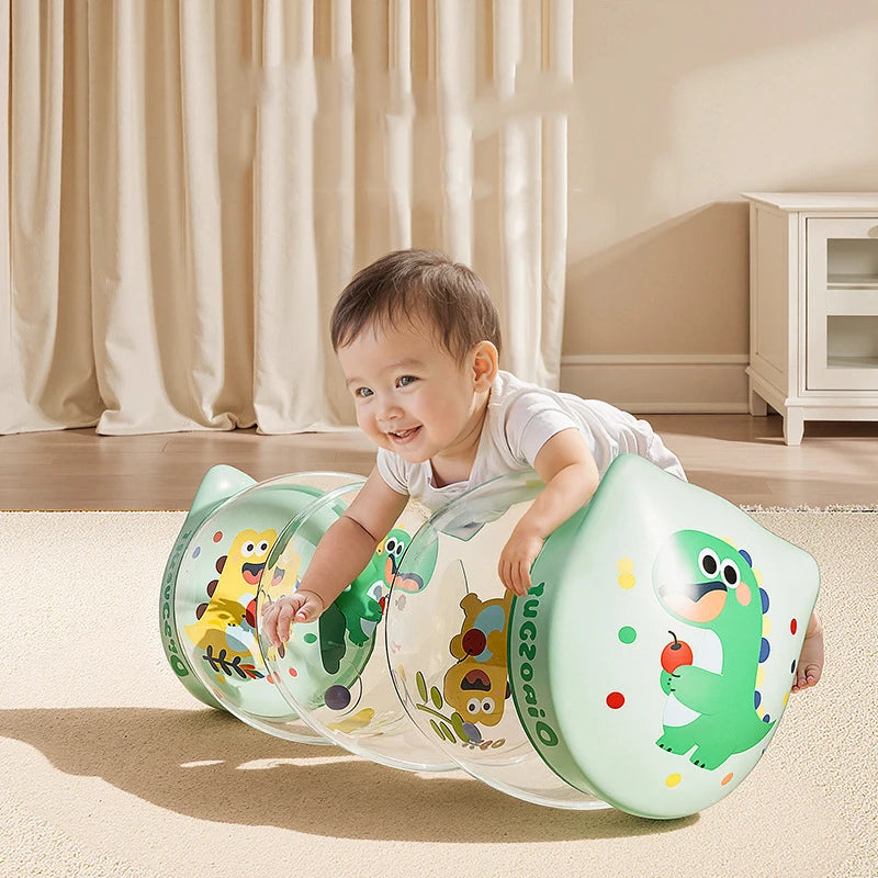A baby is playing with a green Montessori crawling roller toy on a light carpet.