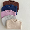 A stack of four knitted baby pullover sweaters in shades of brown, blue, pink, and beige.