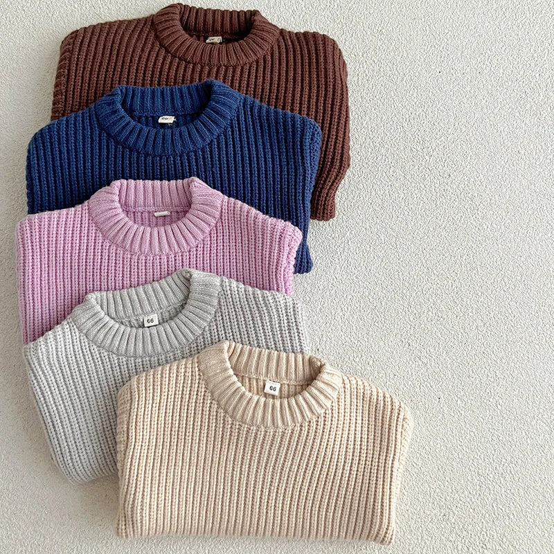 A stack of four knitted baby pullover sweaters in shades of brown, blue, pink, and beige.