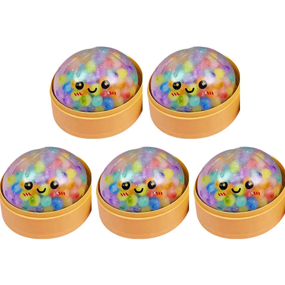 Quatre jouets anti-stress sphériques colorés faits de perles en forme de dumplings souriants.