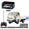 A white RC freight truck model with a flatbed and remote control accessories shown next to its box.