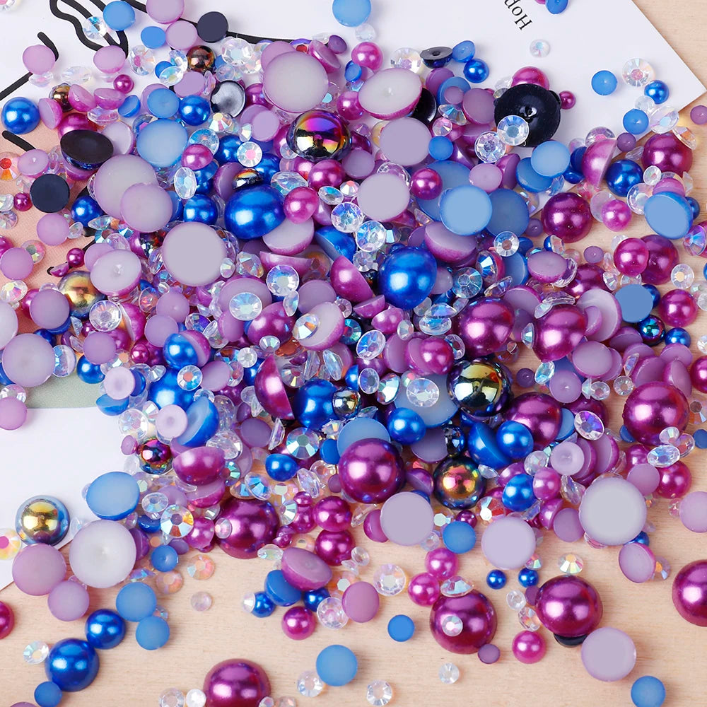 A scatter of mixed resin rhinestone pearls in various shades of purple, blue, and pink on a white surface.