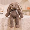 A soft brown bunny plush toy with long ears sitting on a white lace tablecloth.