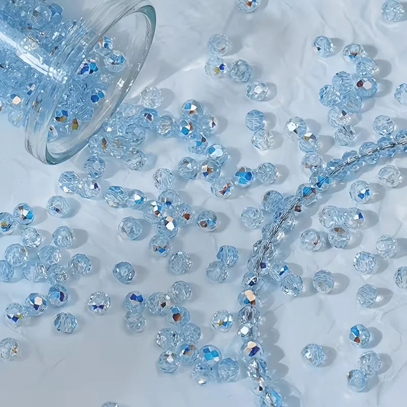 Clear and iridescent blue glass beads scattered on a white surface for jewelry making