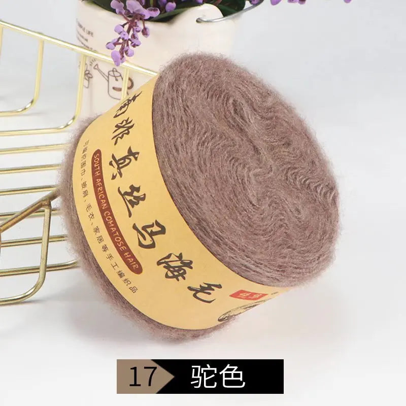 A ball of brown silk mohair blended yarn is displayed next to a gold wire rack.