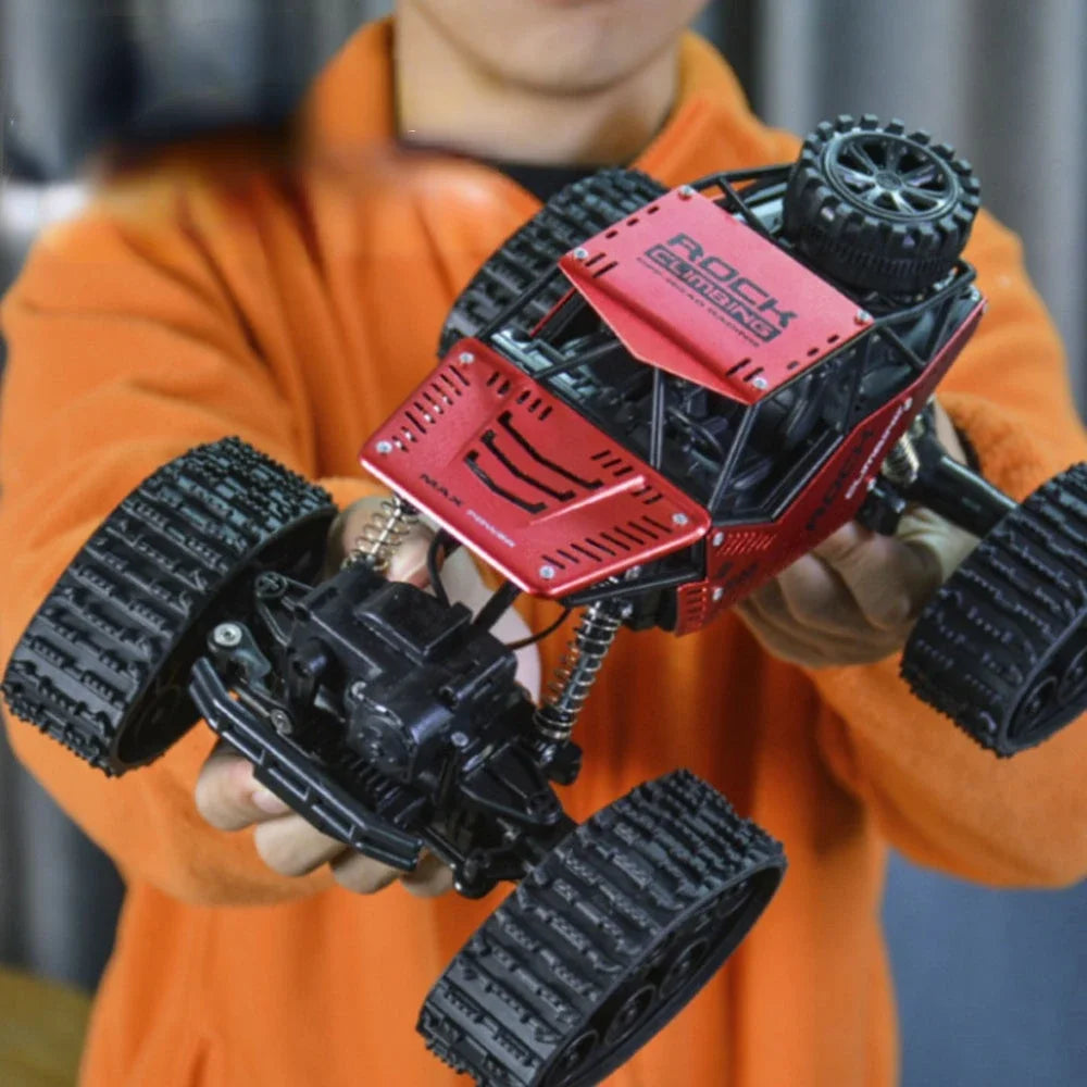 A person holds a red and black 4WD remote control stunt car off-road crawler truck with large tires.