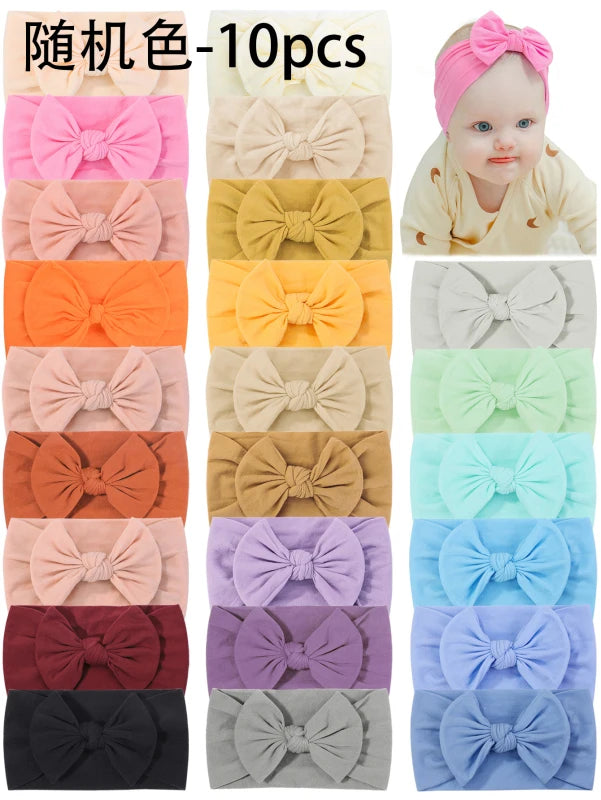 A collection of 10 pink and pastel colored nylon knit bow headbands for baby girls.