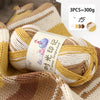 A ball of gradient acrylic yarn in yellow and beige colors is shown on a knitted fabric background.