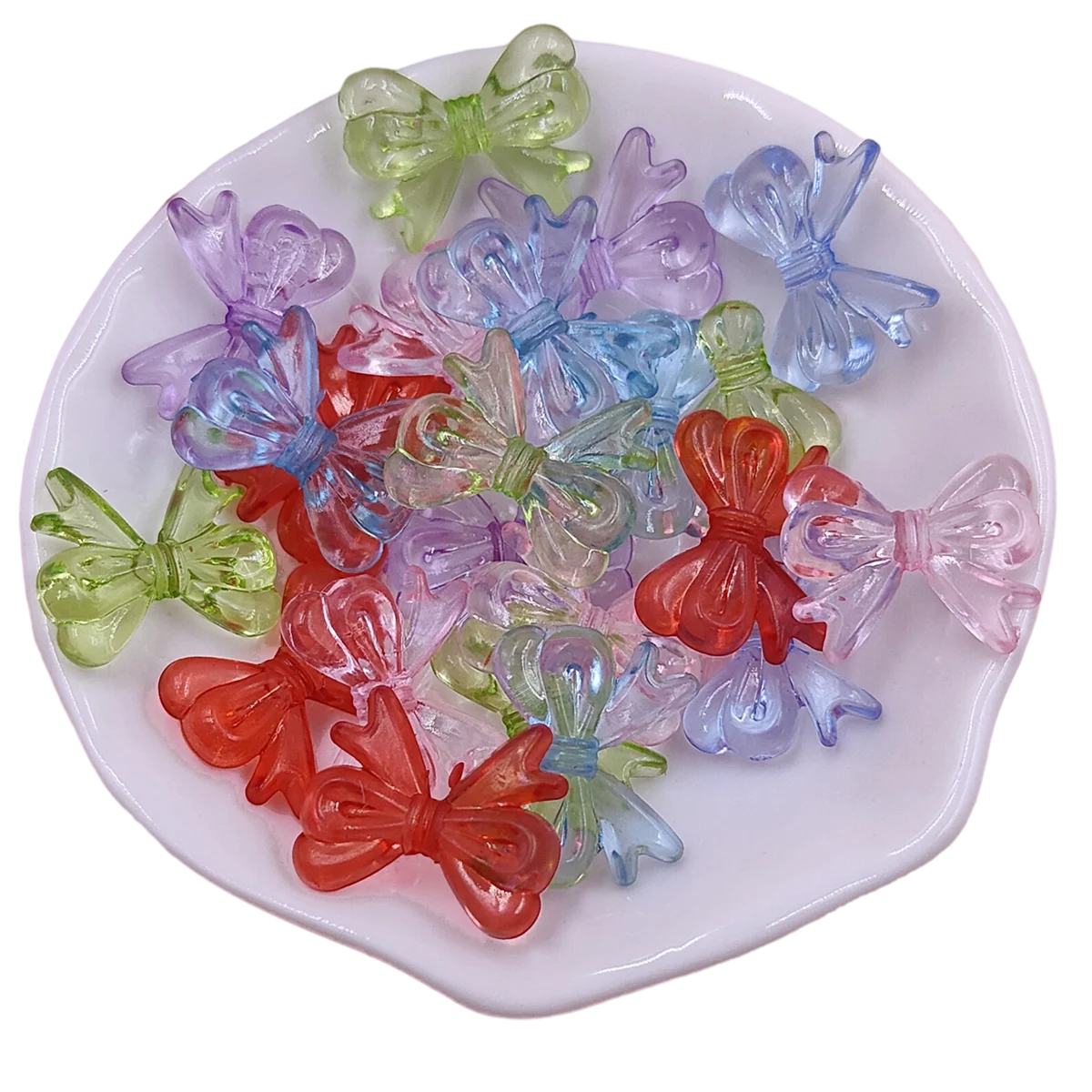 A collection of 20 colorful acrylic bow beads in shades of green, purple, blue, and red arranged on a white plate.