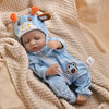 A baby doll wearing a blue striped romper with an animal hood and ears, lying on a beige blanket.