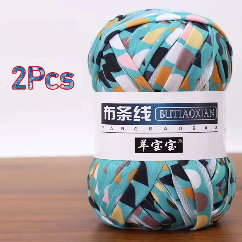 A ball of soft chunky t-shirt yarn in various teal, pink, and green patterns is shown.