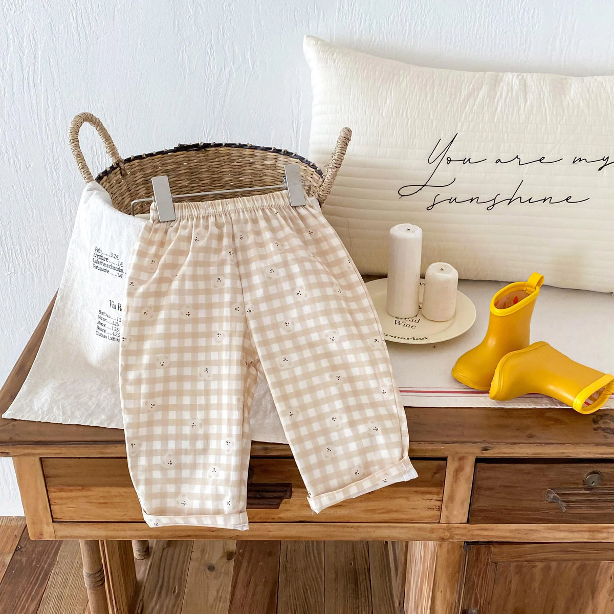 Light beige plaid print casual pants with elastic waist displayed on a wooden table.