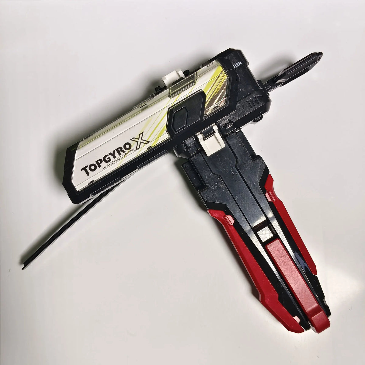 A black and silver TopGyro X gyro launcher accessory with a red grip is shown against a white background.